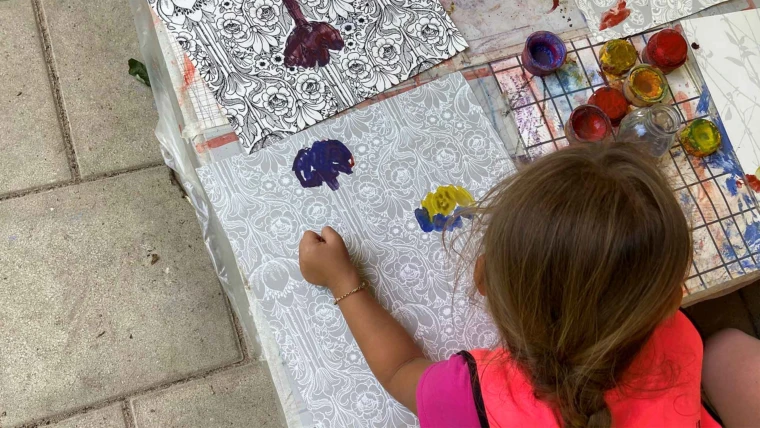 Foto på barn som målar utomhus vid ett lågt bord på Adolfina förskola.