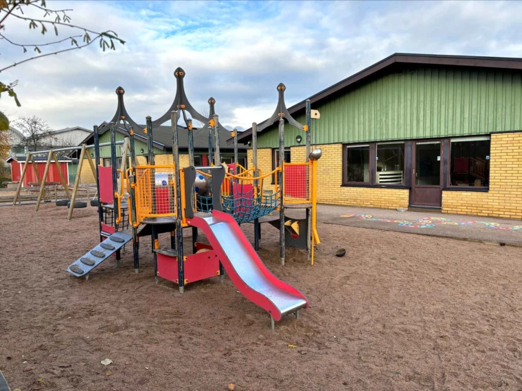 Foto på Ättekulla förskola, vy från gården med lek för yngre och äldre barn.