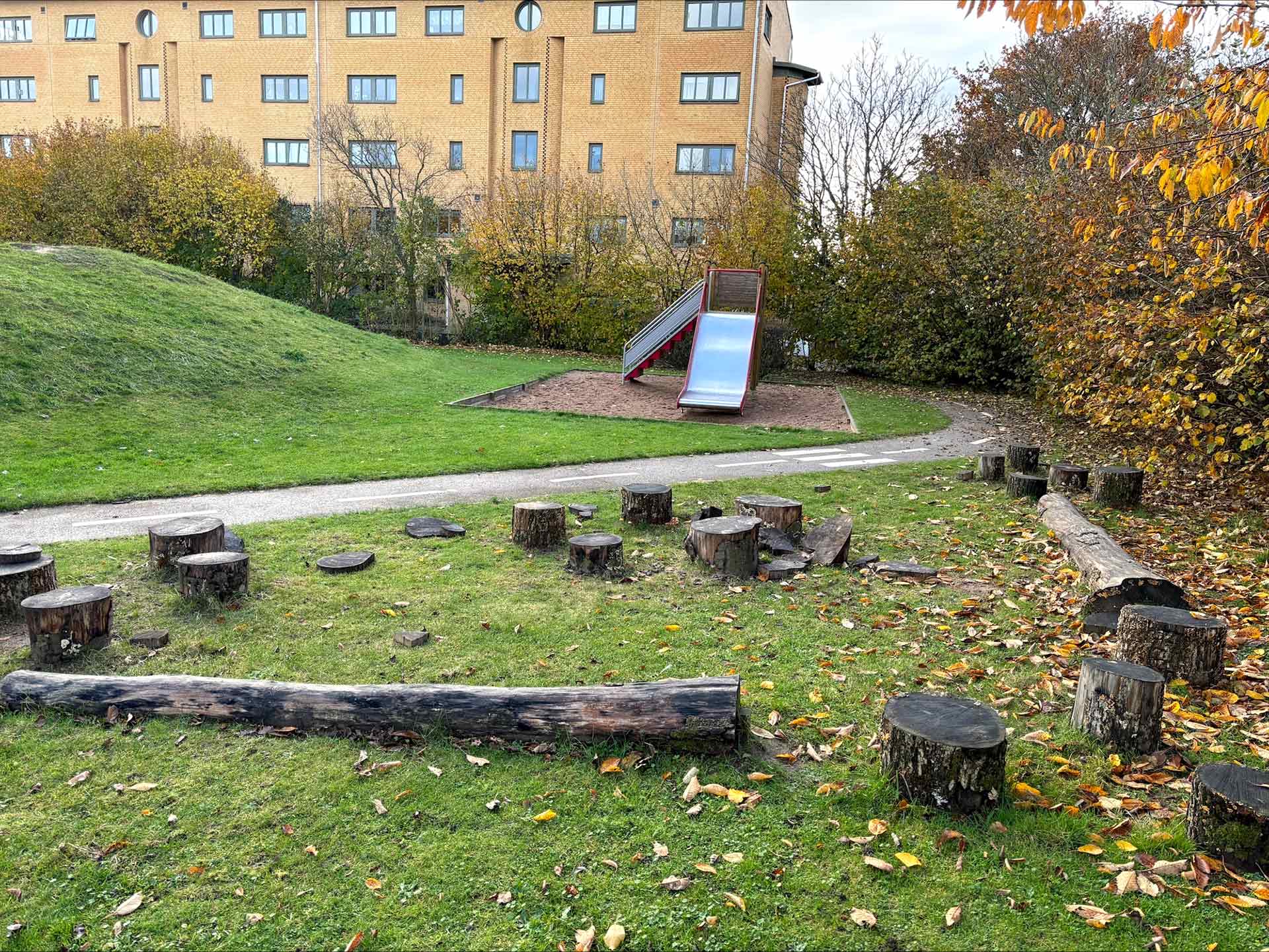 Foto på del av gården på Ättekulla förskola, stora gräsytor och naturmaterial