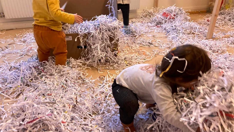 Foto på barn som leker med massor av pappersstrimlor på förskolan.