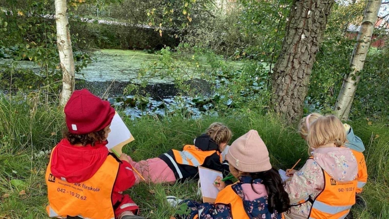 Foto på fyra barn som ritar i naturen