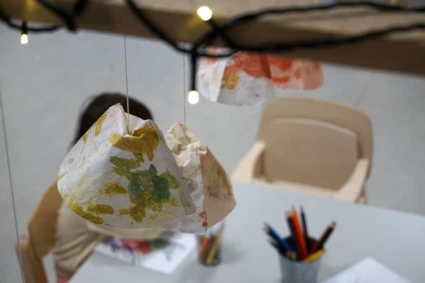 Foto på dekorationer av barnens egna alster som pryder taket tillsammans med en ljusslinga.