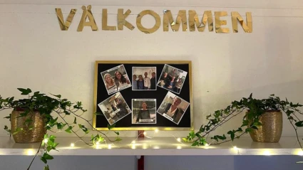 Foto på en vägg på Lussebäckens förskola med ljusslingor, gröna växter och bilder på all personal.