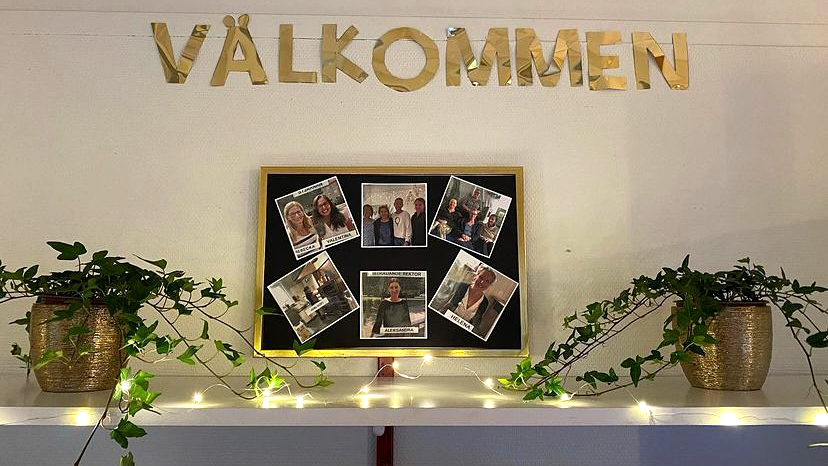 Foto på en vägg på Lussebäckens förskola med ljusslingor, gröna växter och bilder på all personal.