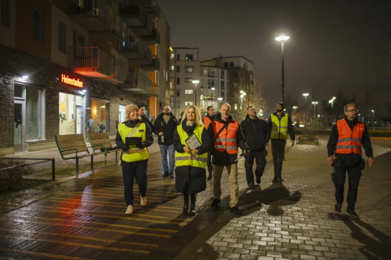 En grupp personer i reflexväst rör sig i ett bostadsområde.