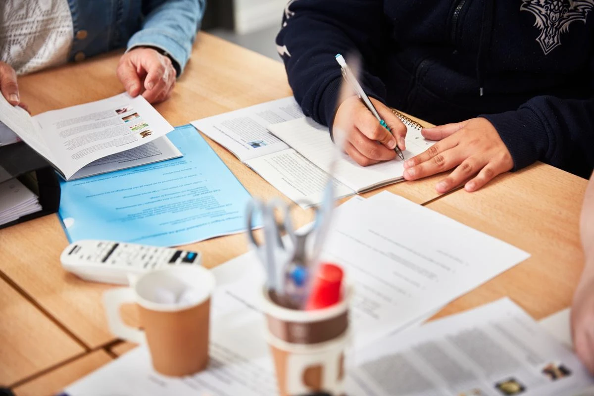 två personer som sitter vid ett bord och studerar.