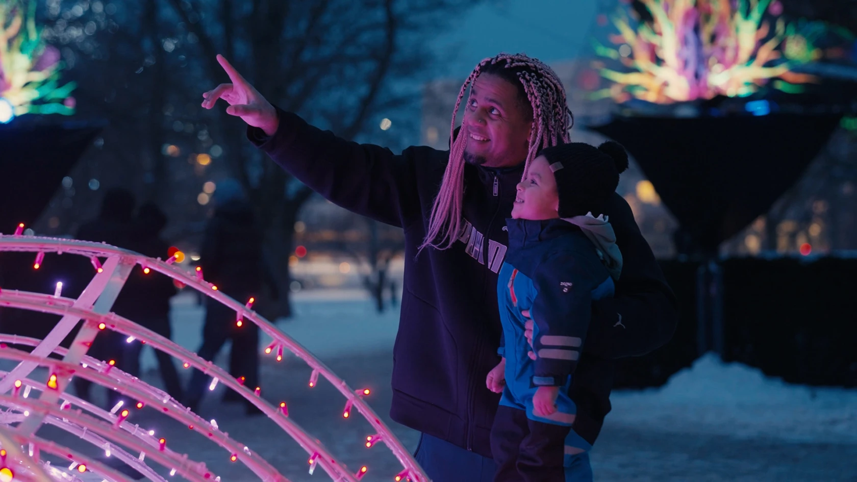 Man och barn tittar på ljusverk i Stadsparken.