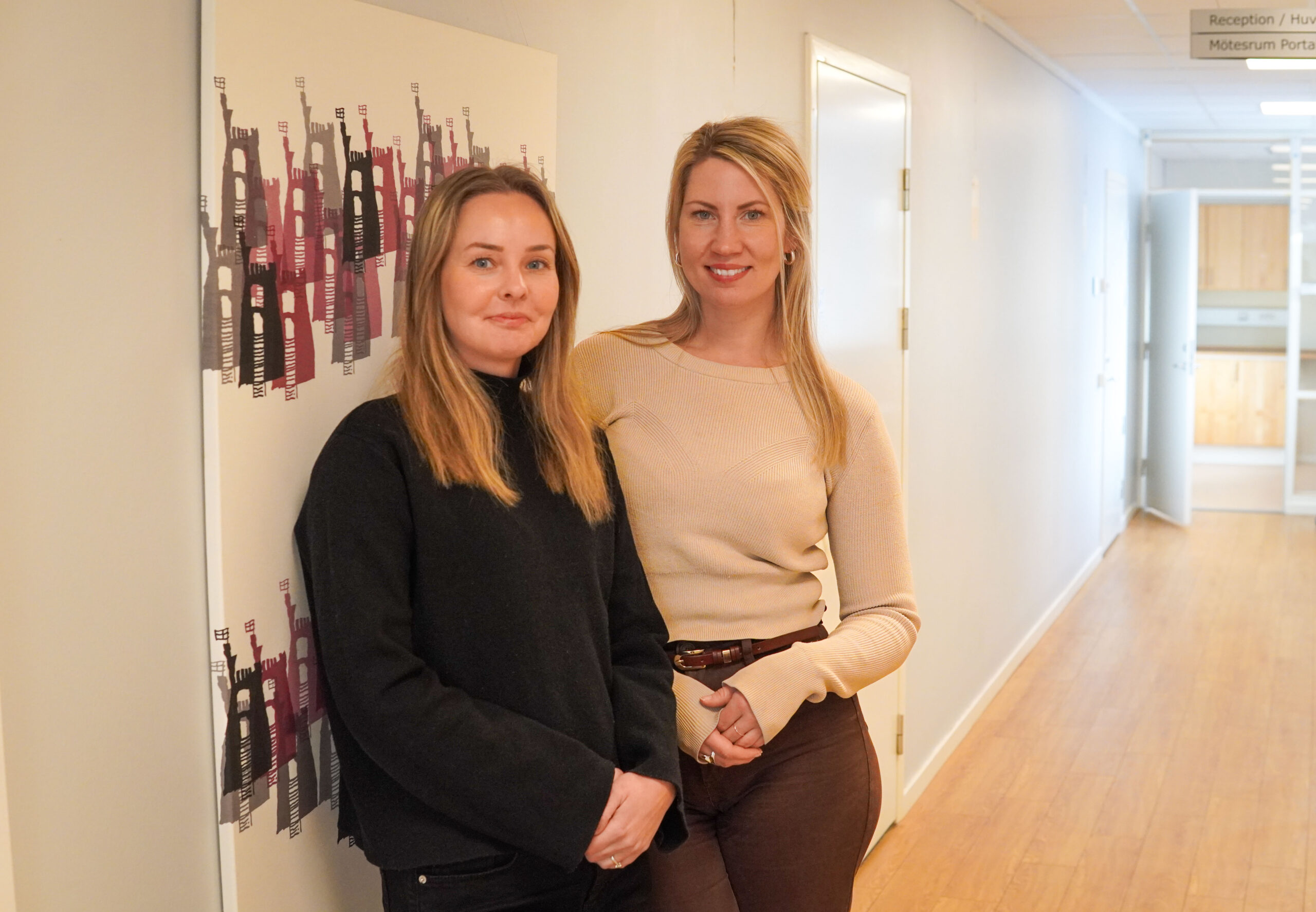 Två kvinnor tittar in i kameran och ler