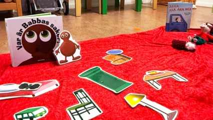 Boken Var är Babbas saker. Bilder på Babbas saker ligger på en röd filt på golvet.