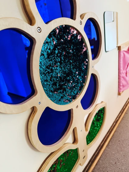 Stor färgglad blomma med paljetter och speglar på väggen.