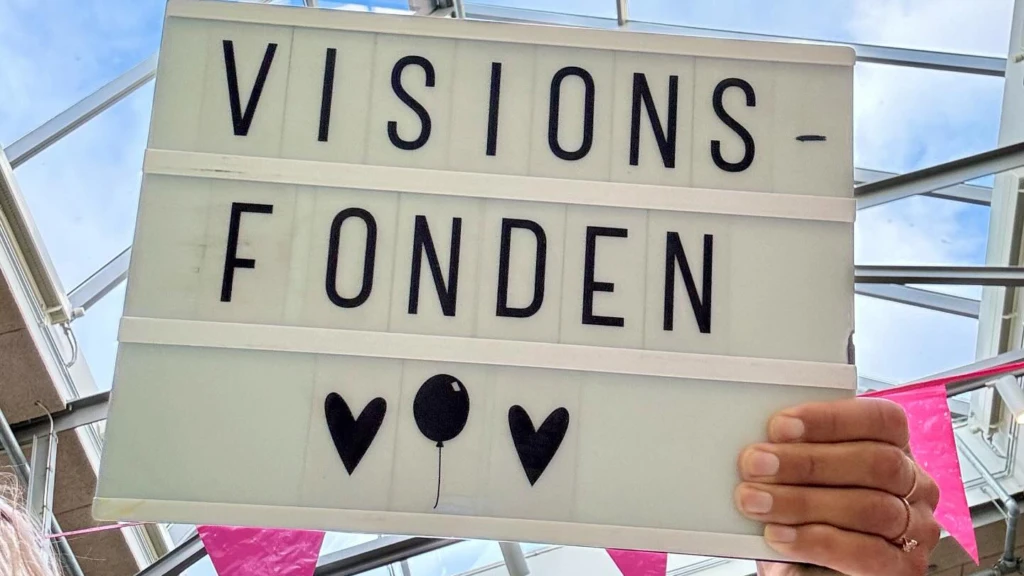 Hans som håller en skylt som det står Visionsfonden på.