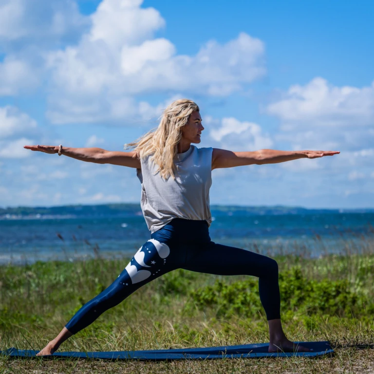 Kvinna som står på yogamatta i krigarposition