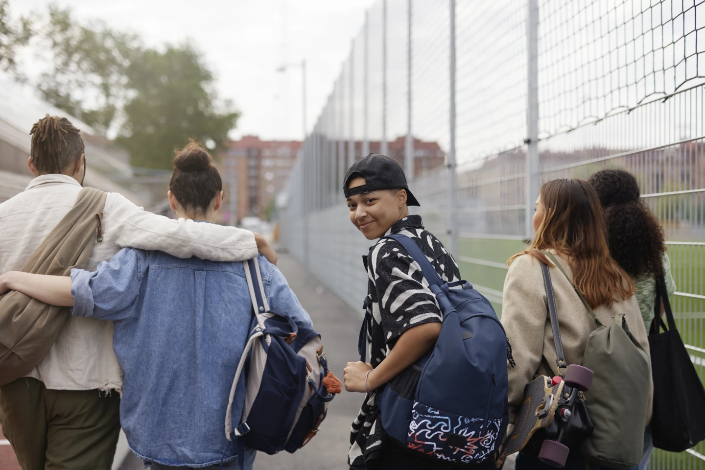 Fem ungdomar i grupp, varav en av dem tittar bak och in i kameran och ler.