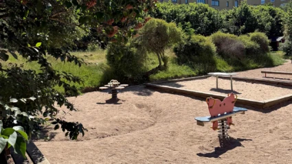 Foto av Ättekulla förskolas gård med sandlådor i tre sektioner omgivna av grönskande träd och buskar.