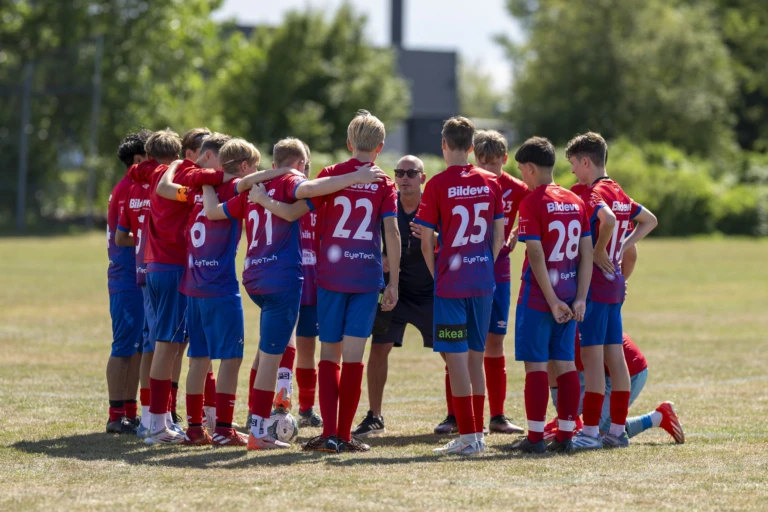 Ett ungt fotbollslag samlat i klunga på en fotbollsplan.