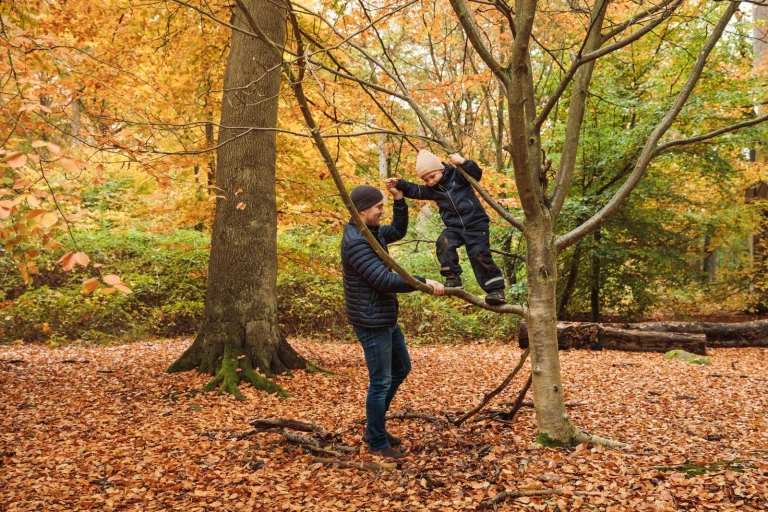 En vuxen och ett barn som leker i en skog.