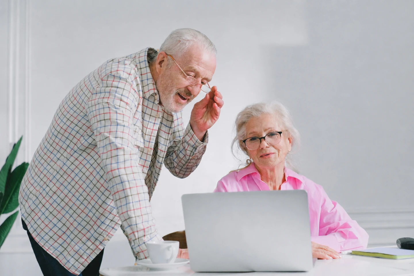 En kvinna sitter bakom en laptop. En man står på vänster sida och tittar på datorskärmen.