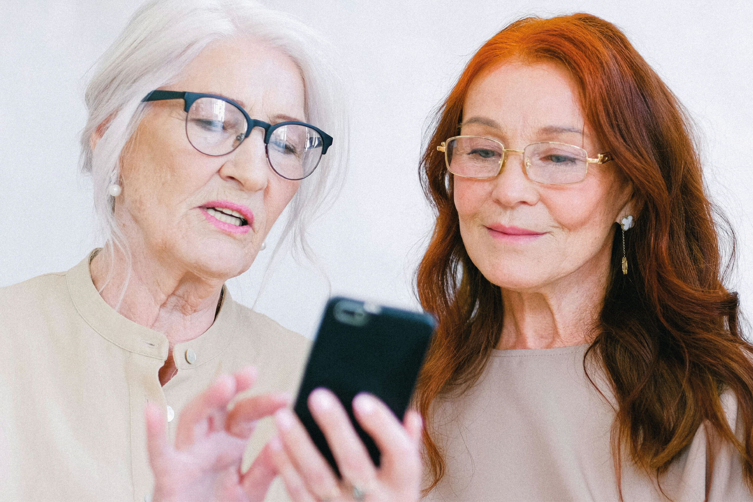 Två kvinnor tittar på en mobiltelefon.