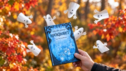 En hand håller i boken Spökhuset. Höstlovets spöken dyker upp ur och runt boken. I bakgrunden syns röda höstträd.
