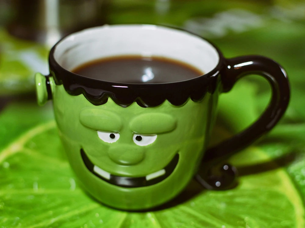 Grön kaffekopp med ett monsteransikte.