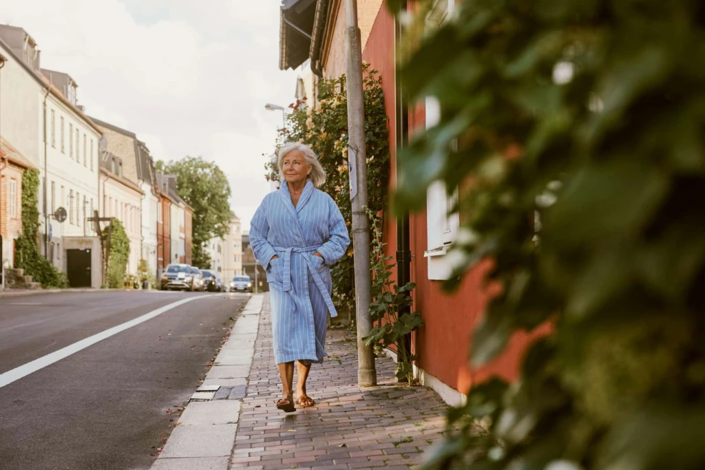 en dam i morgonrock promenerar på en gata i Helsingborg
