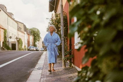 en dam i morgonrock promenerar på en gata i Helsingborg