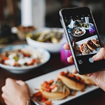 En person tar ett foto med sin mobilkamera på mat uppdukat på ett bord.