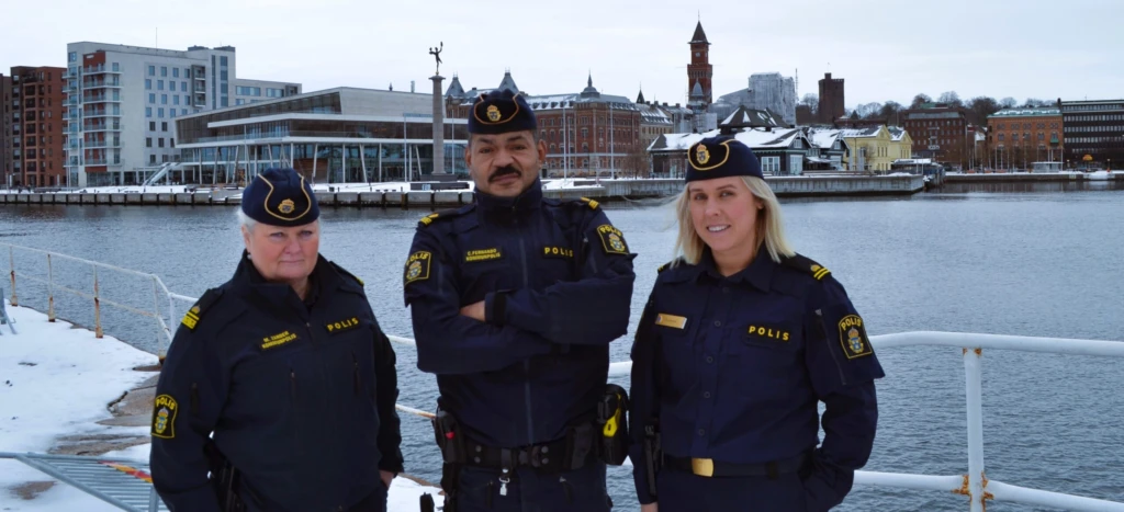 Tre kommunpoliser med staden i bakgrunden.