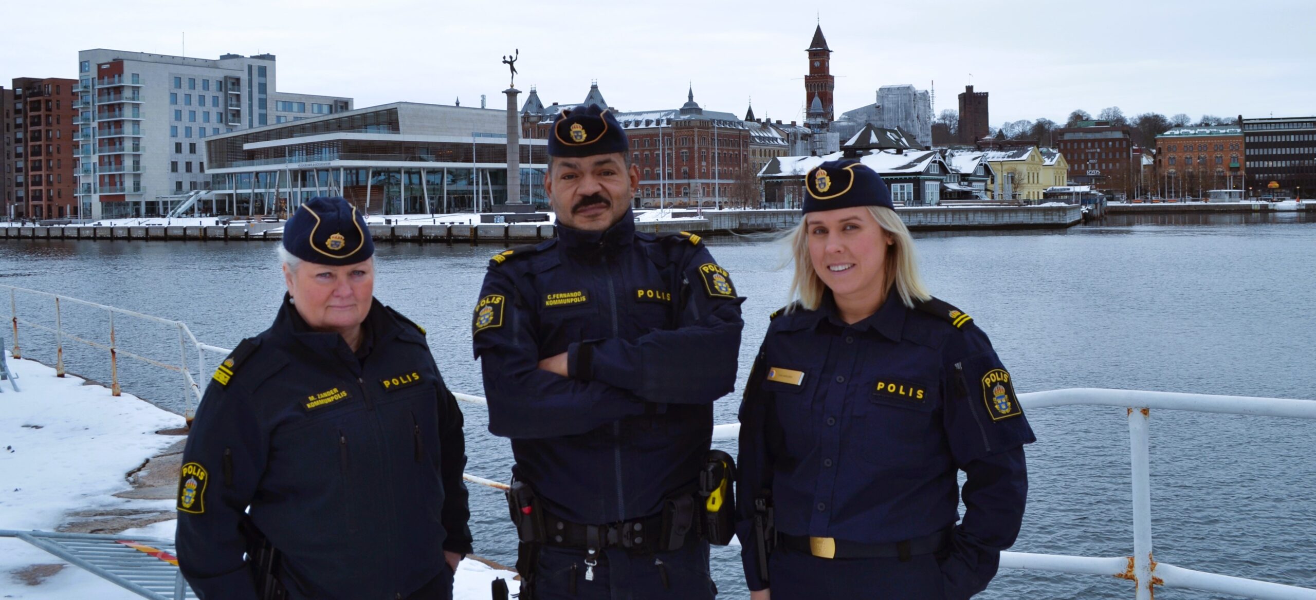 Tre kommunpoliser med staden i bakgrunden.
