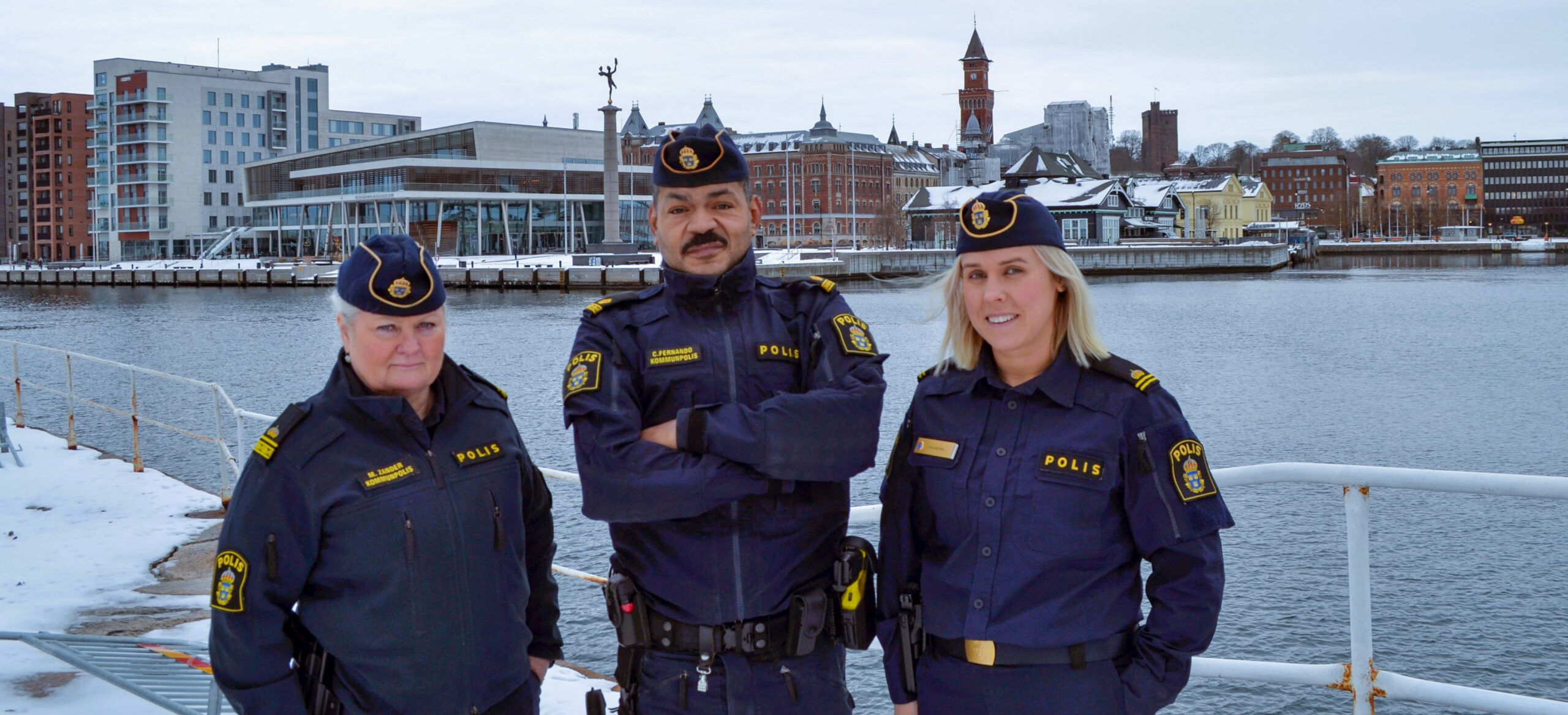 De tre kommunpoliserna med staden i bakgrunden.