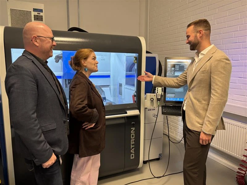 två män och en kvinna i industrilokal.