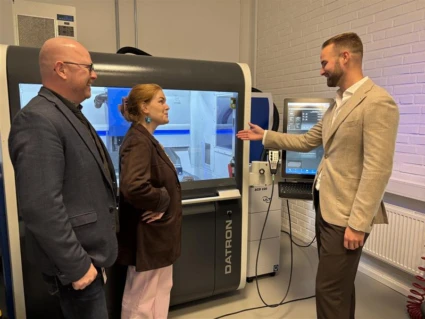 två män och en kvinna i industrilokal.