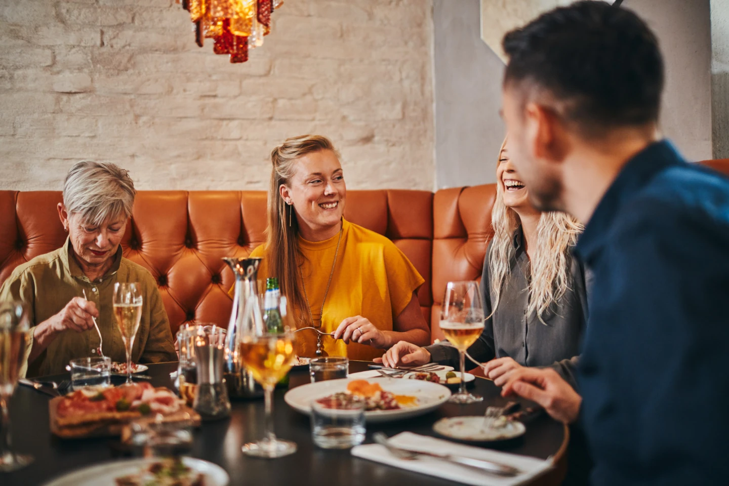 Vänner njuter av en härlig middag tillsammans på restaurang. Skratt och glädje lyser på deras ansikten.