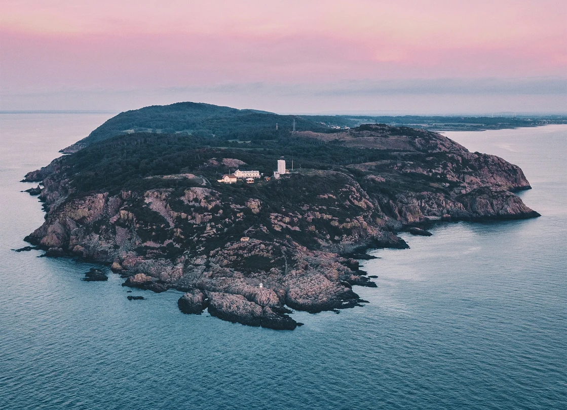 Drönarbild över Kullaberg i kvällsljus, himlen har en rosa ton.