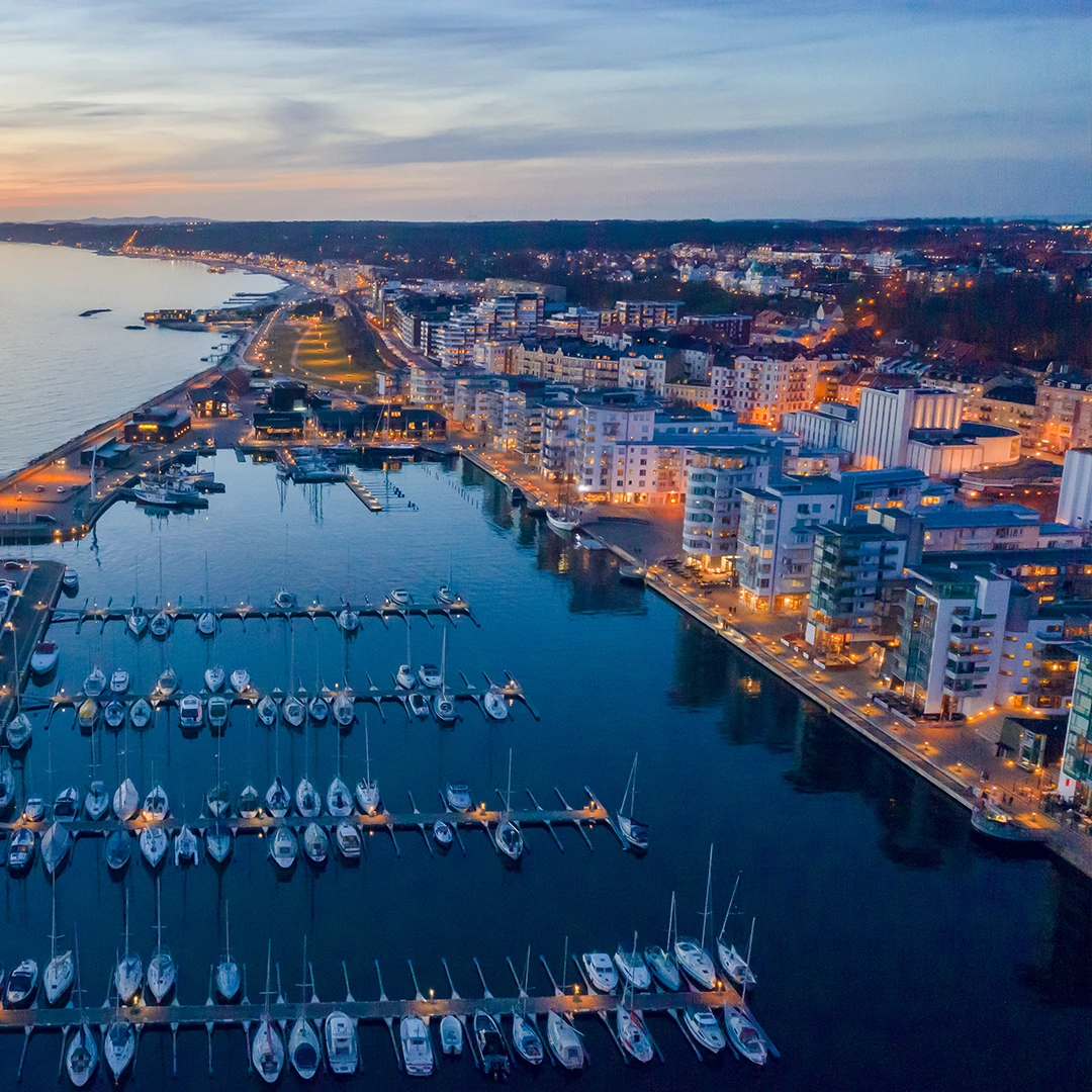 Kvällsbild över norra hamnen. Segelbåtar i hamnen och det lyser fint i fönsterna.