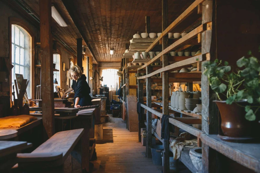 I verkstan på Wallåkra stenkärlsfabrik, bänkar att dreja vid längs en gång med fönster