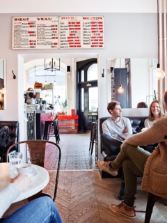 Etoile cafe, ett gäng sitter och pratar vid ett bord. Typisk fransk inredning.