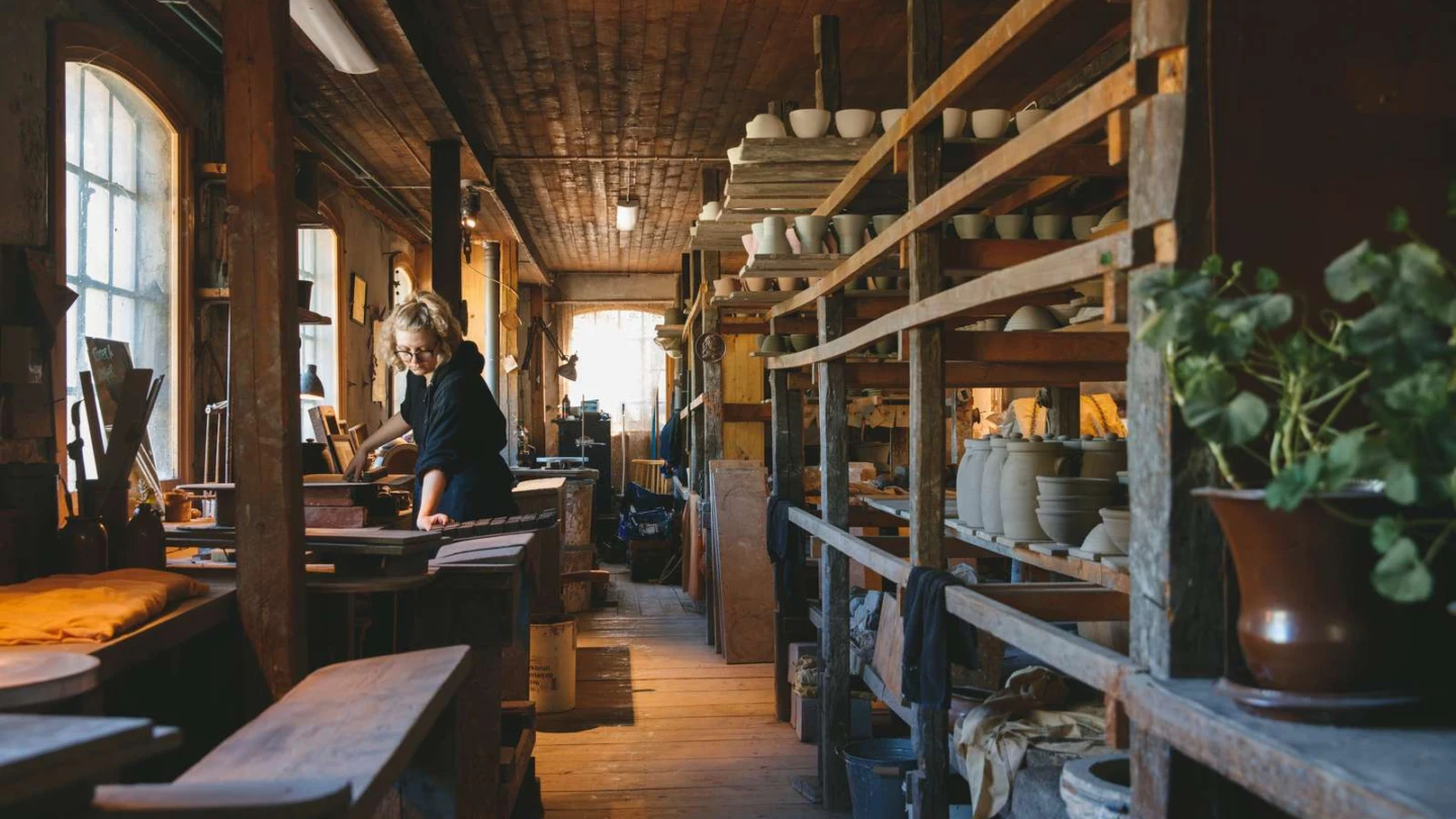 Wallåkra Stenkärlsfabrik i verkstan där all drejning görs. Drejade verk står uppställda på hyllor.