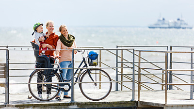 familj på cykel med litet barn vid havet.
