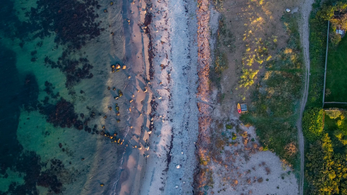 Drönarbild över Kullaleden, en smal stig slingrar sig mellan stranden och gröna områden.