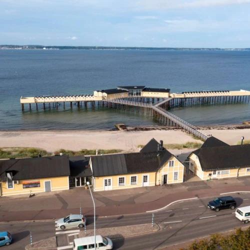 Pålsjöbaden i Helsingborg. Kallbadhus i gul träbyggnad som ligger ute på pålar i sundet.