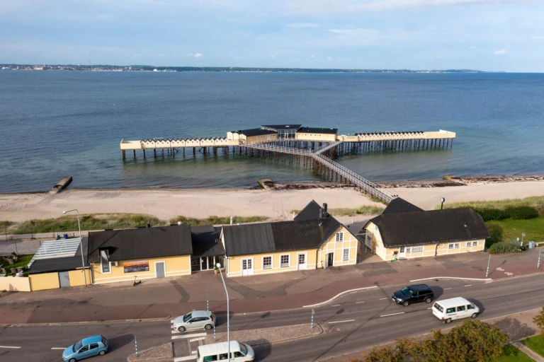 Pålsjöbaden i Helsingborg. Kallbadhus i gul träbyggnad som ligger ute på pålar i sundet.