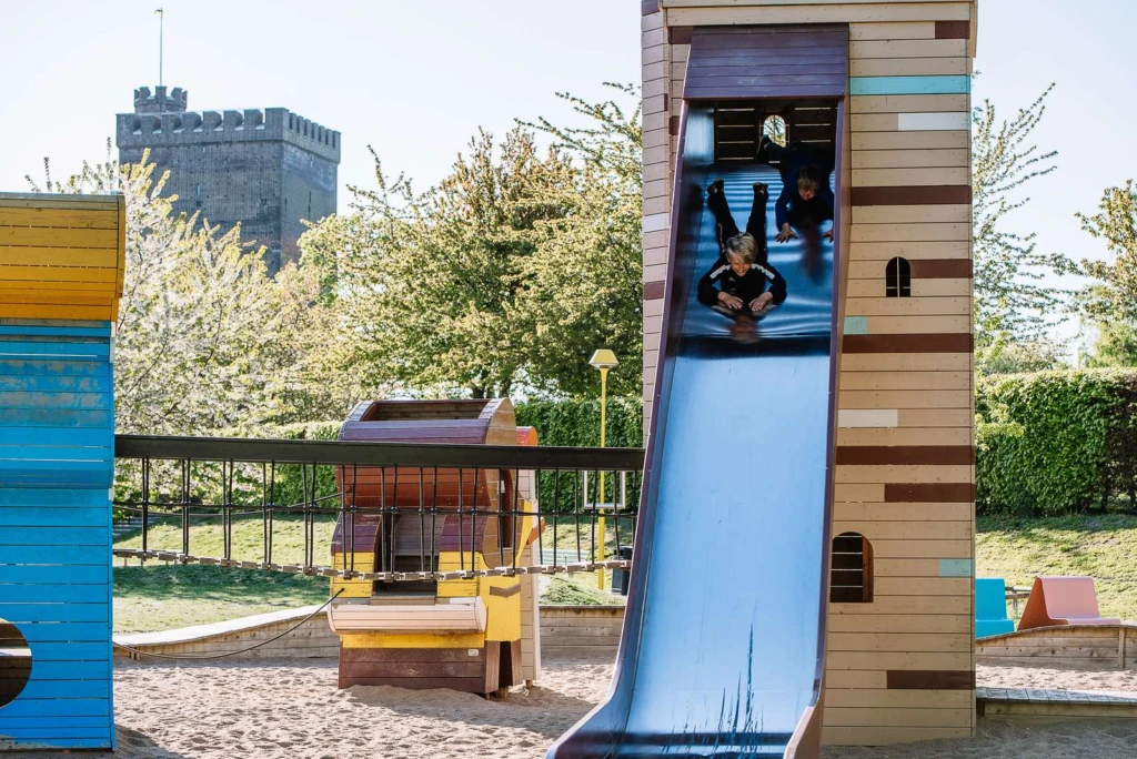 2 barn åker ner för en rutschkana på en lekplats