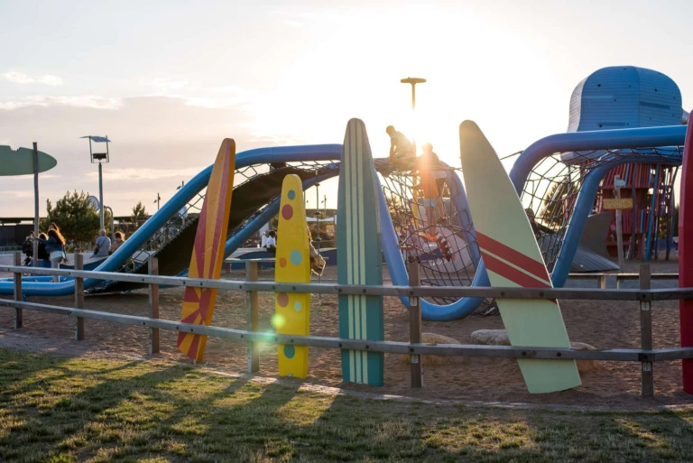 Lekplats med surfbrädor i kvällsljus.