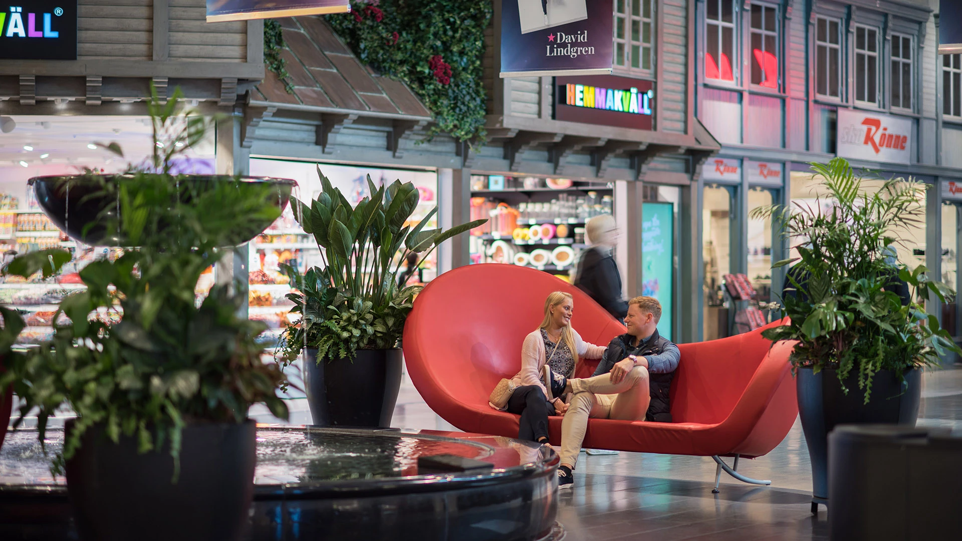 Shoppingcenter väla, ett torg inne på centret med en röd soffa och butiker runt omkring.