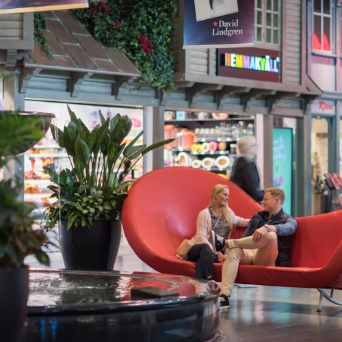 Shoppingcenter väla, ett torg inne på centret med en röd soffa och butiker runt omkring.