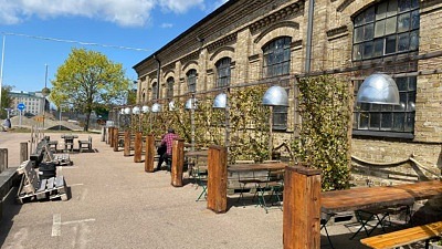 Uteservering på Helsingborgs bryggeri. Bänkar och bord uppradade längs en vacker äldre byggnad.