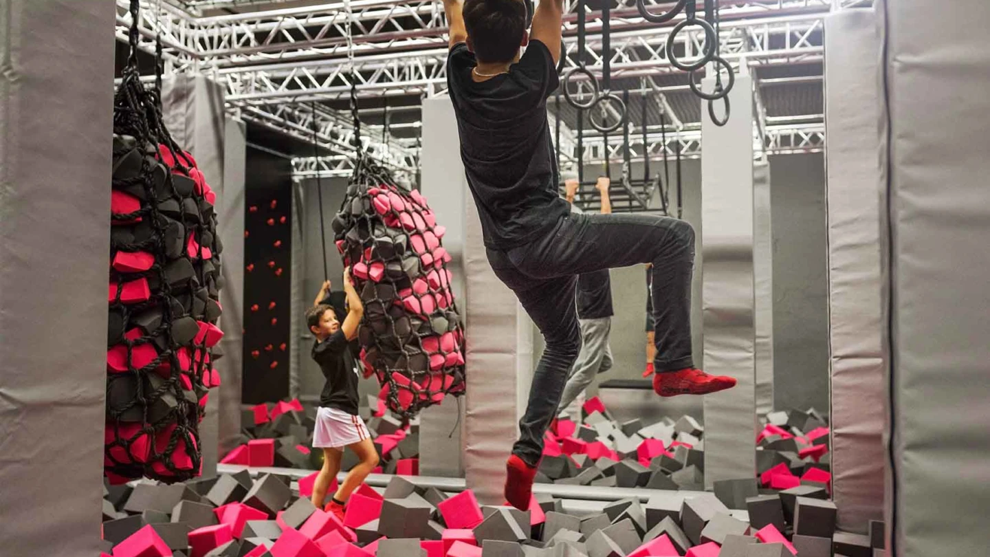 Jumpyard trampolinpark i Helsingborg och deras Ninja Warrior bana. Ett barn hänger i ringarna.