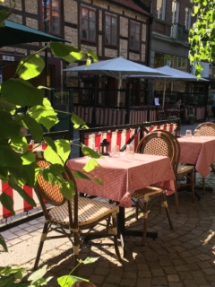 Olsens skaferis uteservering med röda dukar på borden och grönska från träden bredvid.