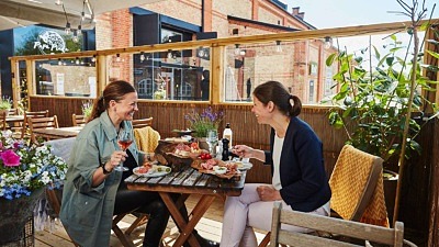 Två tjejer äter på en uteservering på Spritfabriken i Ödåkra. Sommarkänsla och en charkbricka står på bordet.
